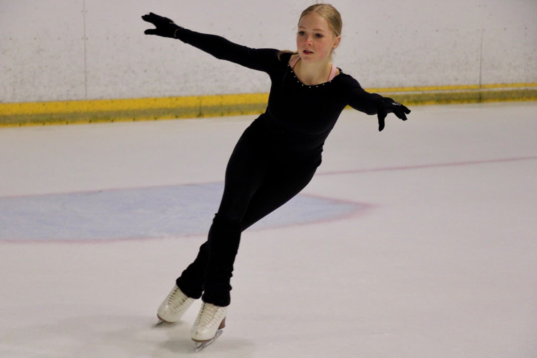 A skater in a deep spiral on the ice at a Yebin Mok camp